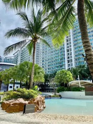 a beach with palm trees and a large building at Staycation in Diamond in Manila