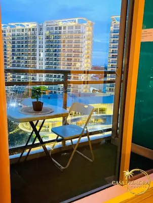 a chair and a table on a balcony with buildings at Azure Staycation by Casa Tremora in Manila
