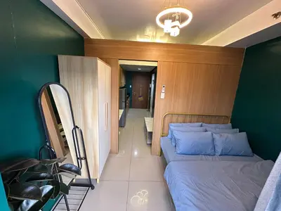 a bedroom with a bed and a green wall at Kathys Crib 11th flr 2 at Shell Residence pool view in Manila