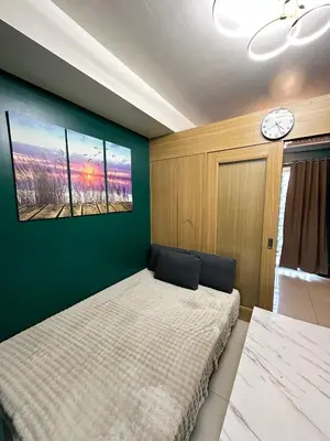 a bedroom with a bed and a clock on the wall at Kathys Crib 11th flr 2 at Shell Residence pool view in Manila