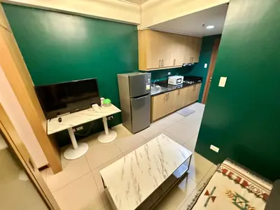 a kitchen with green walls and a desk and a refrigerator at Kathys Crib 11th flr 2 at Shell Residence pool view in Manila