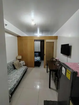 a room with a bed and a desk and a television at Sea Residence Condotel Pasay in Manila