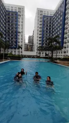 three people in a swimming pool in a city at Sea Residence Condotel Pasay in Manila
