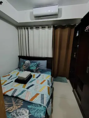 a small bedroom with a bed and a television at Sea Residence Condotel Pasay in Manila