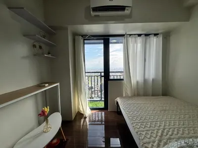 a bedroom with a bed and a large window at Condo in Makati in Manila