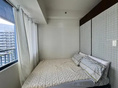 a small bedroom with a bed and a window at Condo in Makati in Manila