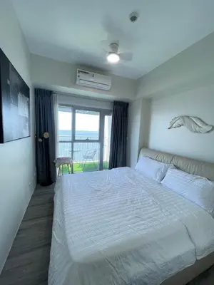 a bedroom with a large white bed and a window at Luxurious Modern 2 Bedrooms Facing Manila Bay Sunset, Airports, Okada, Solaire, MOA with free parking in Manila