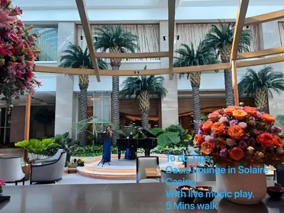 a woman standing at a piano in a lobby with palm trees at Luxurious Modern 2 Bedrooms Facing Manila Bay Sunset, Airports, Okada, Solaire, MOA with free parking in Manila