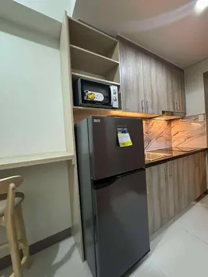a kitchen with a black refrigerator and wooden cabinets at Cozy Minimalist Staycation in Manila
