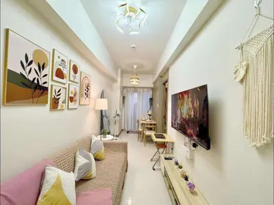 a living room with a couch and a tv on a wall at Horizon Haven in Manila