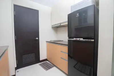 a kitchen with a black refrigerator and a door at 101 Newport Boulevard 1BR with Parking - Pasay City in Manila