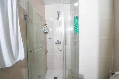 a bathroom with a shower with a glass door at 101 Newport Boulevard 1BR with Parking - Pasay City in Manila
