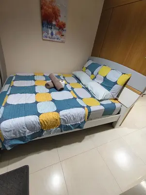 a bed with a blue and yellow comforter and pillows at Shell residences Moa Staycation by jeric in Manila