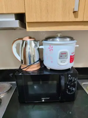 a slow cooker and a pot sitting on top of a microwave at Shell residences Moa Staycation by jeric in Manila
