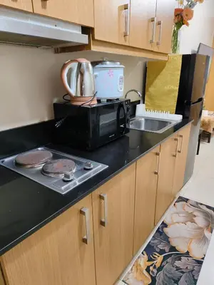 a kitchen with a microwave and a sink at Shell residences Moa Staycation by jeric in Manila
