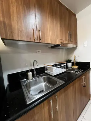 a kitchen with a stainless steel sink and wooden cabinets at MOA GRAND STAY Suite 04 Newly Turn-over Only! in Manila