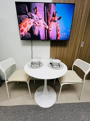 a white table with chairs and a tv on a wall at MOA GRAND STAY Suite 03 Spacious Unit ! in Manila