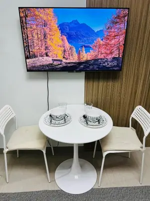 a white table with two chairs and a tv on a wall at MOA GRAND STAY Suite 03 Spacious Unit ! in Manila