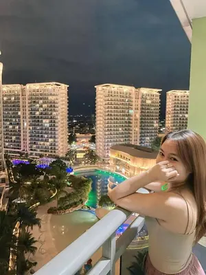 a woman standing on a balcony looking at the city at Staycation in Casitas in Manila