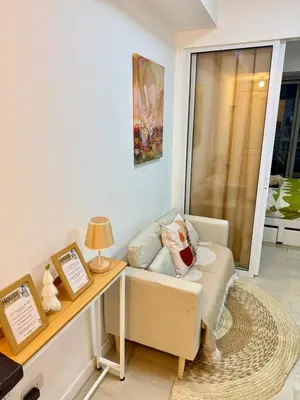 a living room with a couch and a desk with a lamp at Staycation in Casitas in Manila