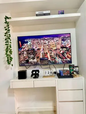 a large tv on a wall with a white desk at Staycation in Casitas in Manila