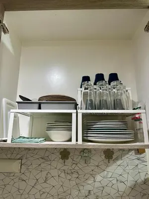 a kitchen shelf with plates and glass jars at Simple Stays at S Residence Pasay in Manila