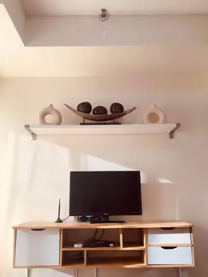 a television on a table with two shelves at Staycation in Bloom in Manila