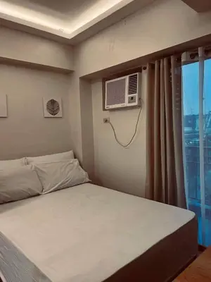 a bedroom with a bed and a window with a air conditioner at Staycation in Bloom in Manila