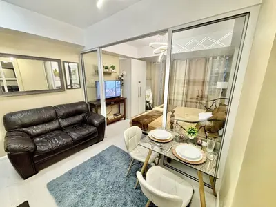 a living room with a black leather couch and a table at Staycation in Casa Joaquin in Manila