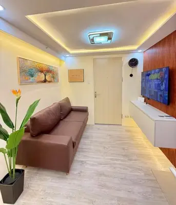 a living room with a brown couch and a tv at Family Game Night 2BR PS4 Netflix Disney in Manila