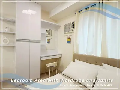 a bedroom area with a bed with a window and a chair at GV Holiday Homes - Shore Residences MOA - Cozy 1BR Apartment in Manila