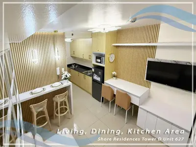 a kitchen with a counter and a table with chairs at GV Holiday Homes - Shore Residences MOA - Cozy 1BR Apartment in Manila
