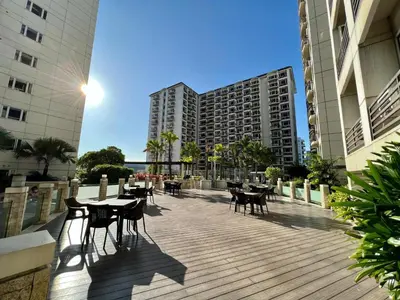 a wooden deck with tables and chairs and buildings at Solemare parksuites tower C in Manila