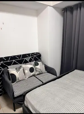 a bedroom with a bed with black and white pillows at Solemare parksuites tower C in Manila