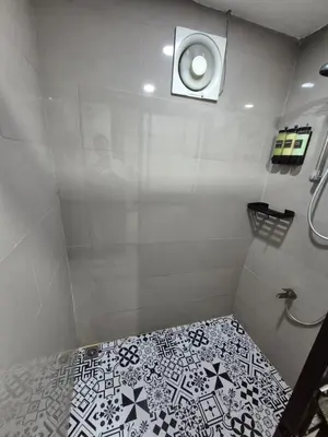 a bathroom with a shower with a black and white tile floor at Layover at 1146 in Manila