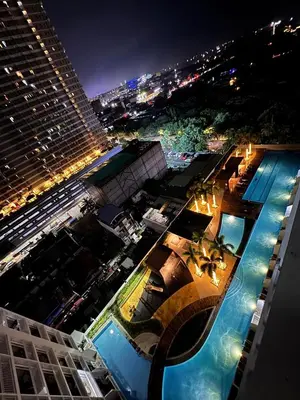 a view of a building with a swimming pool at night at The Metro Breeze - Staycation in Manila