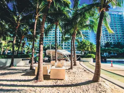 a park with palm trees in front of a building at Celestial Shores Staycation at Azure Resort in Manila