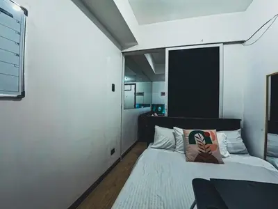 a bedroom with a bed with a black headboard at Celestial Shores Staycation at Azure Resort in Manila