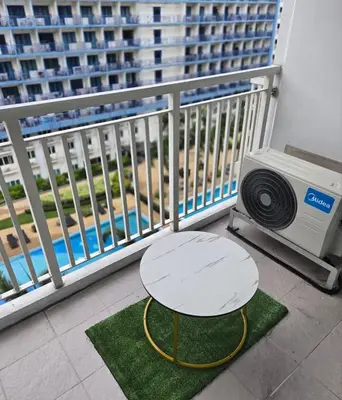 a table on a balcony with a table and a television at Sea Residence - 2 Bedrooms - 5 mins walk to MOA 1A in Manila