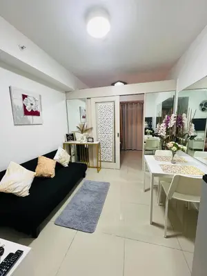 a living room with a black couch and a table at Allie's Cozy Place in Manila