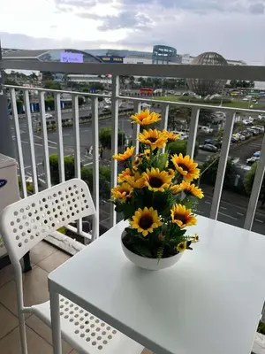 a vase of yellow flowers on a table on a balcony at Staycation Near Mall of Asia in Manila