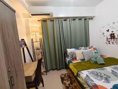a bedroom with green curtains and a table and a bed at Staycation Near Mall of Asia in Manila