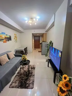 a living room with a couch and a flat screen tv at Staycation Near Mall of Asia in Manila