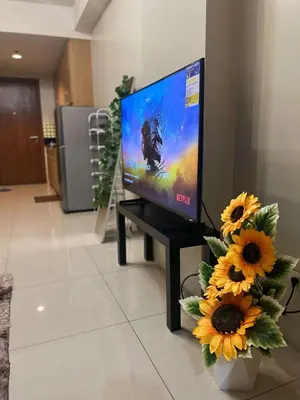 a flat screen tv sitting on a table with sunflowers at Staycation Near Mall of Asia in Manila