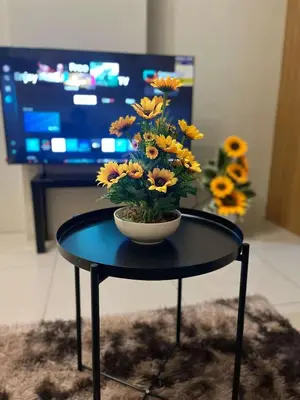 a vase of flowers on a table with a tv at Staycation Near Mall of Asia in Manila