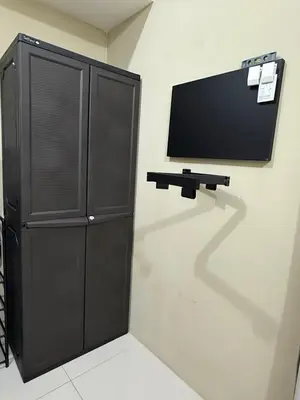 a black cabinet with a flat screen tv on a wall at Convertible Double Studio in Salcedo Village in Manila