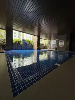 a large swimming pool with blue tiles in a building at Convertible Double Studio in Salcedo Village in Manila