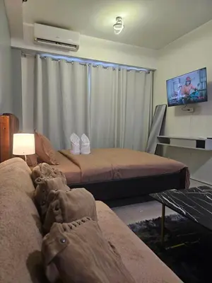 a living room with two beds and a tv at SM Mall Of Asia Shore Residences Vianny in Manila