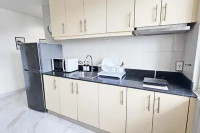 a kitchen with white cabinets and a black refrigerator at 2 Bedroom Condo in Front of SM Mall of Asia in Manila
