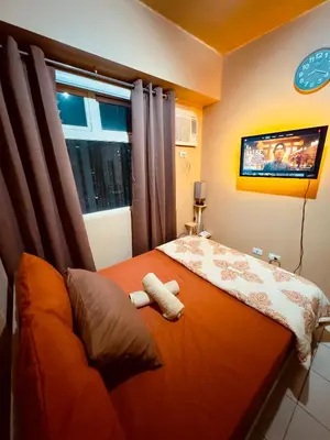 a bedroom with a bed with a tv on the wall at PaulBert's Cabins I in Manila